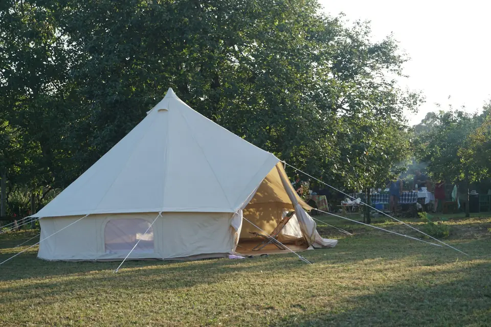 Witte klokvormige tent op een grasveld onder bomen