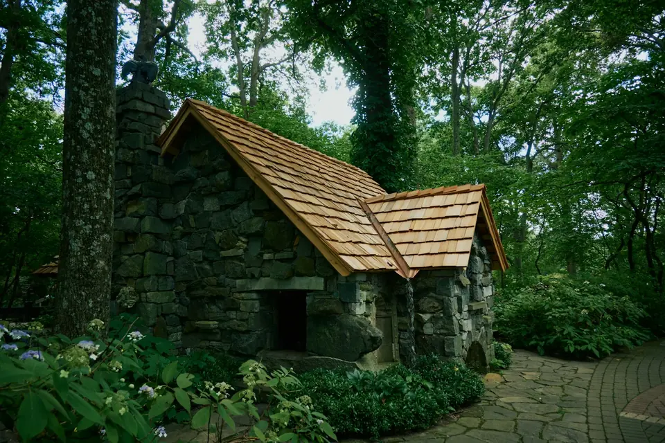 Stenen huisje met houten dak in een bos